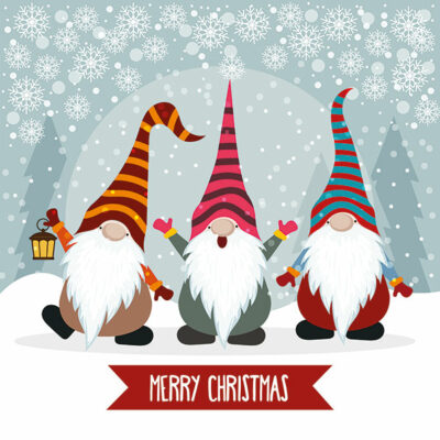 The illustration depicts three gonks with different coloured hats standing out in the snow, with a blue background and moon silhouette. One gonk is holding a lantern. A red banner with the words Merry Christmas is under the gonks feet.